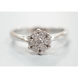 A modern 18ct white gold and seven stone diamond set flower head cluster ring, size O/P, gross