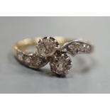 A yellow metal and two stone diamond set crossover ring, with diamond set shoulders, size J, gross