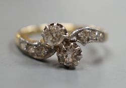 A yellow metal and two stone diamond set crossover ring, with diamond set shoulders, size J, gross
