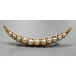 An early 20th century yellow metal and graduated cultured pearl set crescent brooch, 40mm, gross