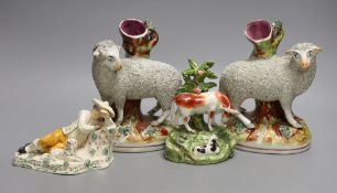 A pair of Staffordshire sheep spill vases, 19 cm high, a similar cow group and a recumbent man and