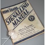 A silver Air Raid Precautions badge and Homeguard signalling manual