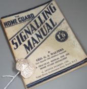 A silver Air Raid Precautions badge and Homeguard signalling manual