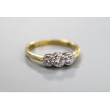 A modern 18ct gold and collet set three stone diamond set ring, size O, gross 3.8 grams, total