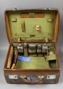 A late Victorian leather travelling vanity case containing five repousse silver topped glass