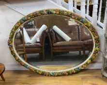 A large oval floral encrusted wall mirror, width 112cm, height 85cm