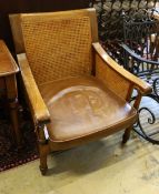 A walnut caned hardwood armchair with brown leather seat, width 75cm, depth 62cm, height 90cm