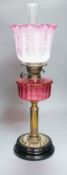 A 19th century cranberry and brass oil lamp with original cranberry shade, height 65cms including