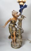 An Art Nouveau style figural lamp, with an amber glass flambe shaped shade, 77cms high including