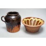 A 19th century slipware bowl and brown glazed single handled storage jar, 21cm tall, (2)