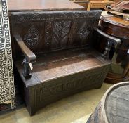 An 18th century carved oak box seat settle incorporating old timber, length 120cm, depth 44cm,