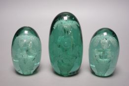 Three green glass dump paperweights, tallest 14cms high