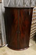 A George III mahogany bowfront hanging corner cabinet with bronze mount, width 66cm, depth 44cm,