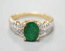 A modern 18ct gold and single stone emerald set dress ring, with diamond chip set shoulders, size R,