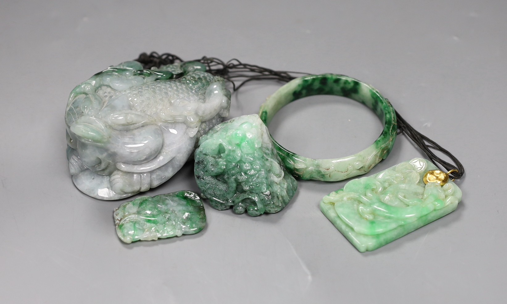 A group of five Chinese jadeite carvings, including two pendants and a bangle, largest 11cms long