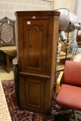 A small early 19th century pine two door standing corner cabinet, (lacking back leg) width 58cm,