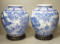 A pair of large Japanese blue and white vases, on wood stands, 26cms high of including stand.