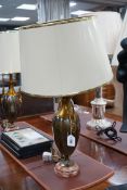 A pair of metal two handled table lamps on marble bases with cream shades, 75cms high,