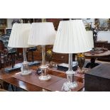 A pair of steel column table lamps, with matching cream silk shades and another similar lamp and