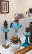Three blue glass oil lamps and a clear glass oil lamp, tallest 62cms high,