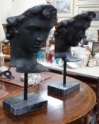 A pair of bronze masks of youths, raised on marble plinths,78cms high,