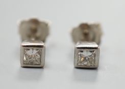 A pair of 750 white metal and princess cut solitaire diamond set ear studs, gross weight 2.4 grams.