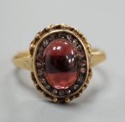 A Victorian style yellow metal cabochon garnet and rose cut diamond set oval cluster ring, size N/O,