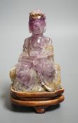A 19th century amethyst and green quartz carving of a seated buddha on hardwood stand. Height 12cm