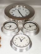 An Alessi wall clock and three similar smaller wall dials