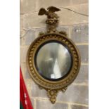 A large Regency carved giltwood convex wall mirror with eagle pediment, replaced plate, width