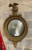 A large Regency carved giltwood convex wall mirror with eagle pediment, replaced plate, width