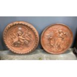 Two circular terracotta plaques embossed with cherubs and classical figures, larger diameter 54cm