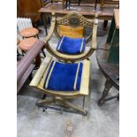 A classical style gilt x-frame elbow chair, width 73cm, depth 52cm, height 96cm and a matching