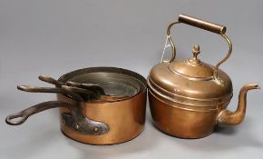 A group of graduated copper pans together with a brass kettle