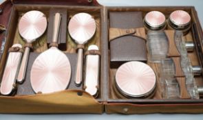A George V travelling toilet case, containing eleven silver and pink enamel mounted glass bottles