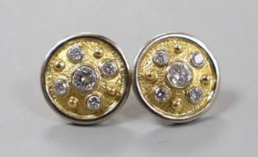 A modern pair of textured yellow metal and diamond cluster set disc earrings, with white metal