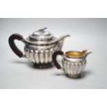 A Chinese Straits? demi fluted white metal teapot and cream jug, with rosewood handles and bird