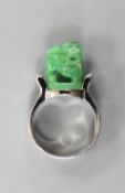A 585 white metal and jadeite ring, carved with a lion dog, size O, gross weight 11.1 grams.