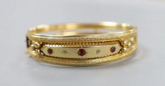 An Edwardian 9ct gold and three stone garnet and two stone diamond chip set hinged bangle, gross