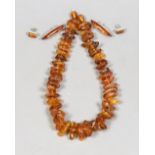 A single strand graduated amber pebble necklace, 42cm and two pairs of white metal mounted amber