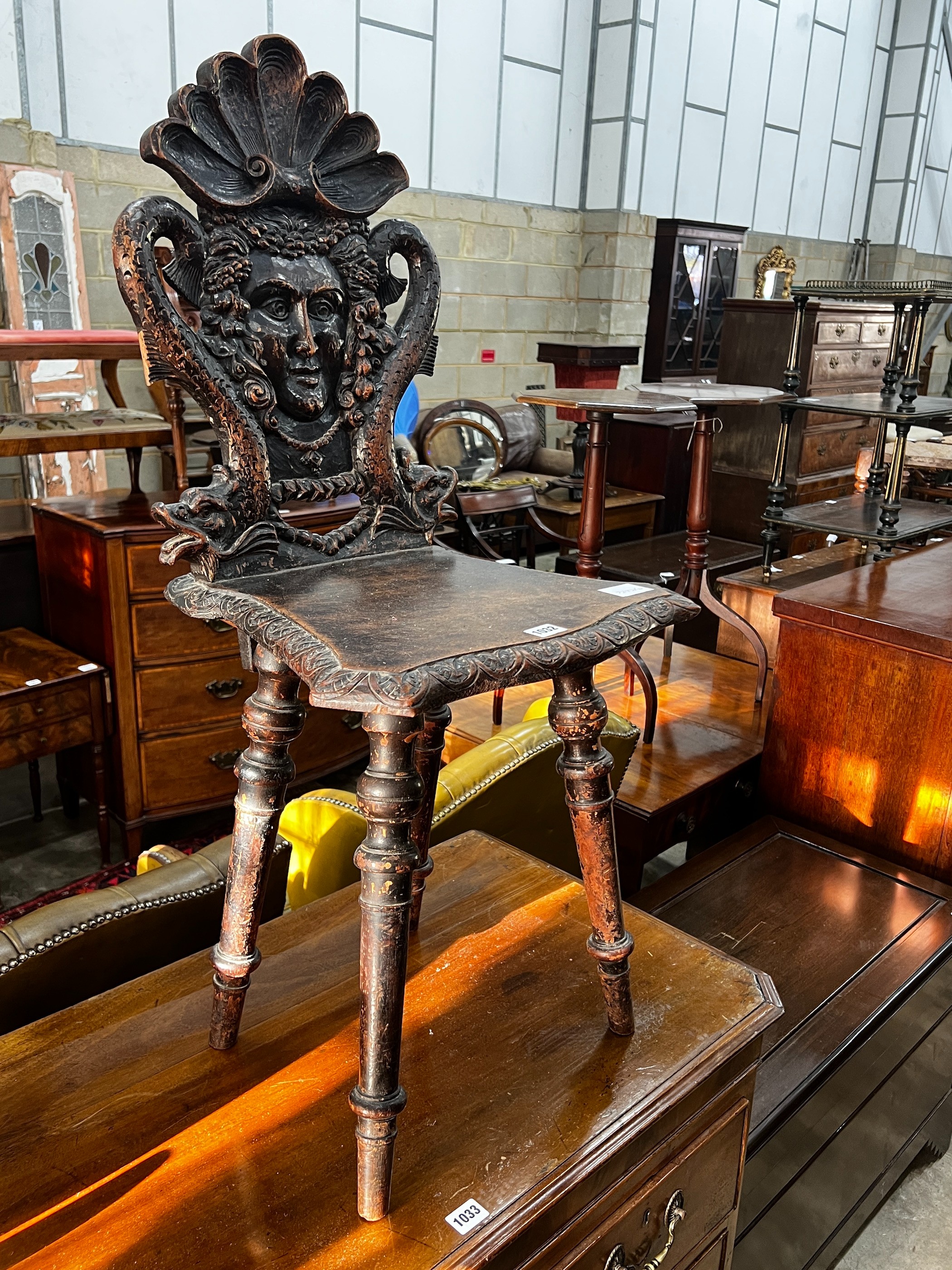 A 19th century Tyrolean oak hall chair, the back carved with a mask, a shell and serpents, height