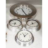 An Alessi wall clock and three similar smaller wall dials