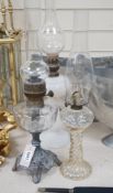 Three oil lamps, two with glass bases, tallest 56cms high,