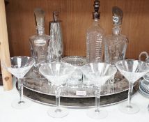 A stylish oval chromed metal two handled tray, with assorted decanters, glassware and cocktail