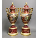 A pair of ornate Vienna style two handled urns bearing covers, with painted love scene and red