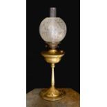 An Edwardian brass oil lamp, with etched glass globe, duplex mechanism and Art Nouveau embossed