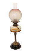 An Edwardian brass oil lamp with cut glass reservoir and pink tinted etched glass globe and flue,