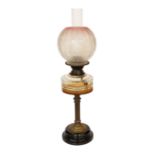 An Edwardian brass oil lamp with cut glass reservoir and pink tinted etched glass globe and flue,