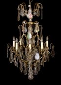 An early 20th century French bronze and cut glass twelve light chandelier, hung with tear, lozenge