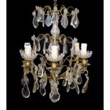 An early 20th century French bronze and cut glass six light chandelier hung with tear and lozenge